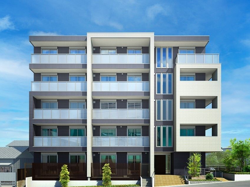 草木が植えられた敷地内には5階建ての建物が建っている。白とブラウン、ライトブルーの外壁でベランダもある。