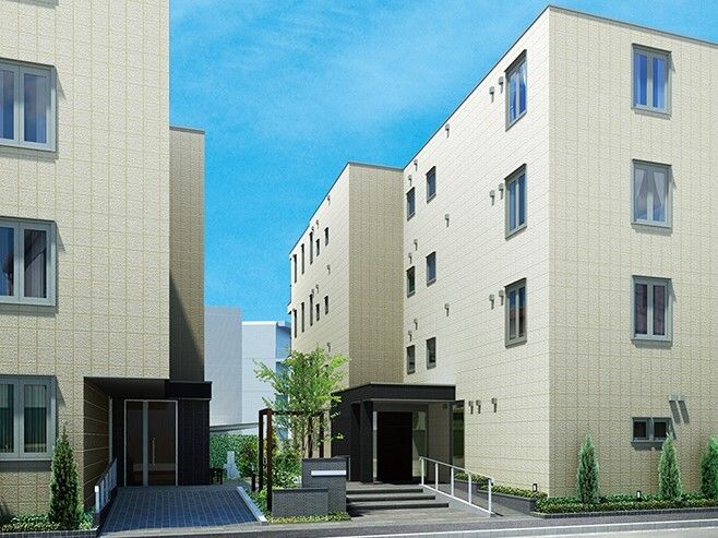 ベージュ系の建物が二つ並んで建っていて、それぞれの玄関に手すり付きのスロープが付いている。