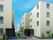 ベージュ系の建物が二つ並んで建っていて、それぞれの玄関に手すり付きのスロープが付いている。