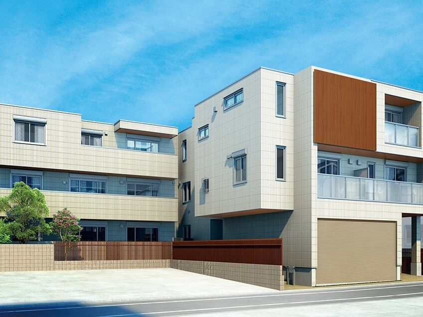 各フロアにベランダがある、ベージュ系の3階建ての建物。敷地内には緑が植えられ、駐車場もある。