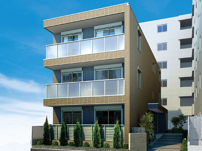 各フロアにベランダがある3階建ての建物の周りには草木が植えられ、外壁はブラウンのレンガ調。