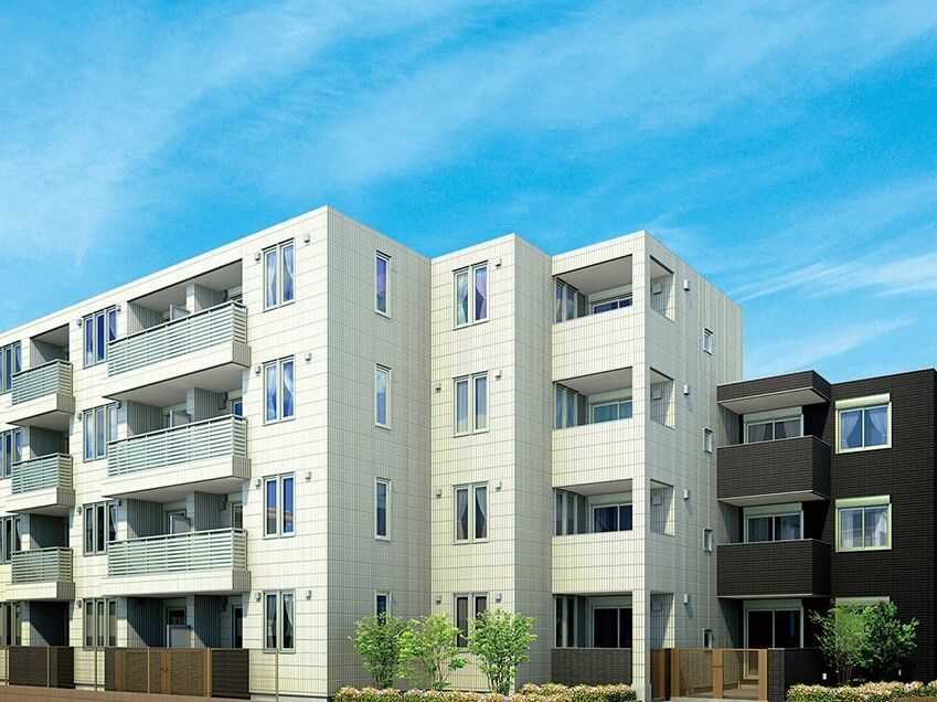 青い空の下に建っている4階建ての建物は白を基調としていて、周囲には草木や花が植えられている。