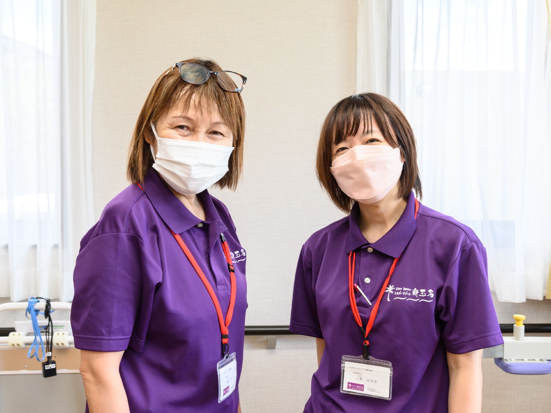 なにかを指さして笑顔で話している車いすの女性とそれを押している介護スタッフの様子