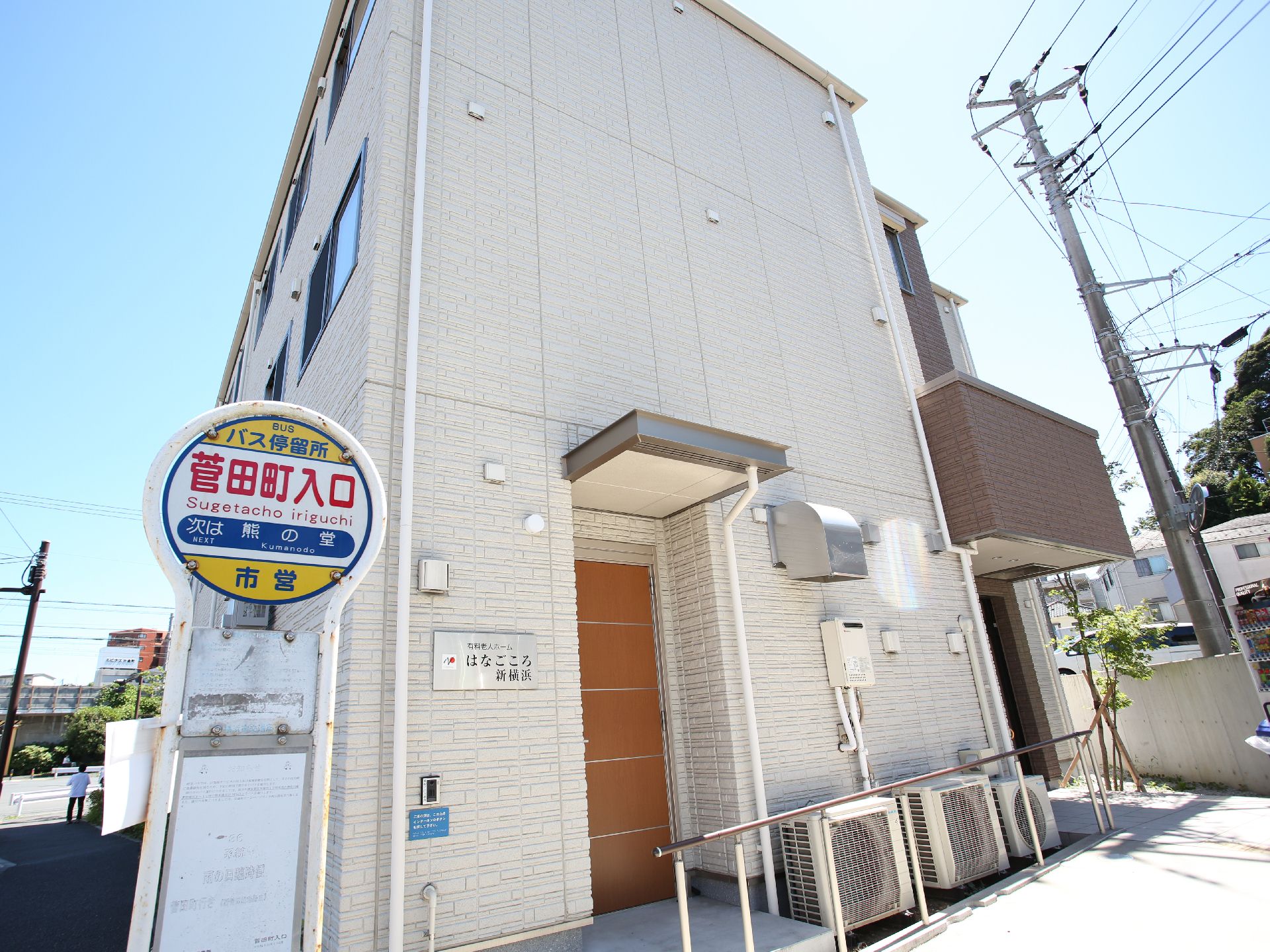 屋外で笑顔で過ごしている車いすの高齢女性に寄り添い、手を添えているエプロンを付けた若い女性スタッフ。