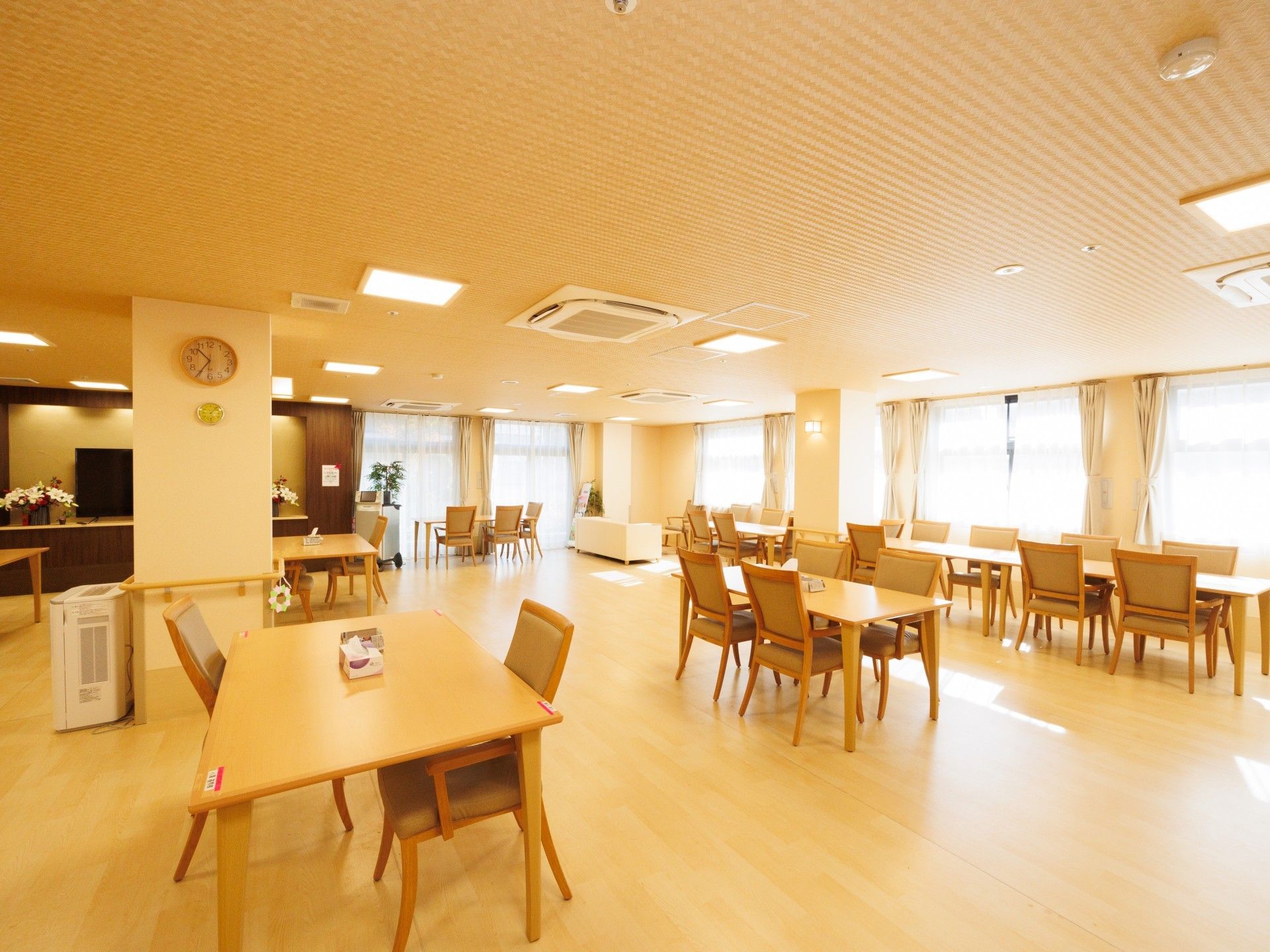 高齢者の方にタオルをかけてマッサージしているスタッフと振り返りながら会話する女性の様子