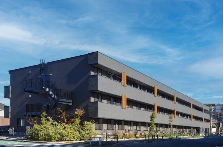 なにかを指さして笑顔で話している車いすの女性とそれを押している介護スタッフの様子