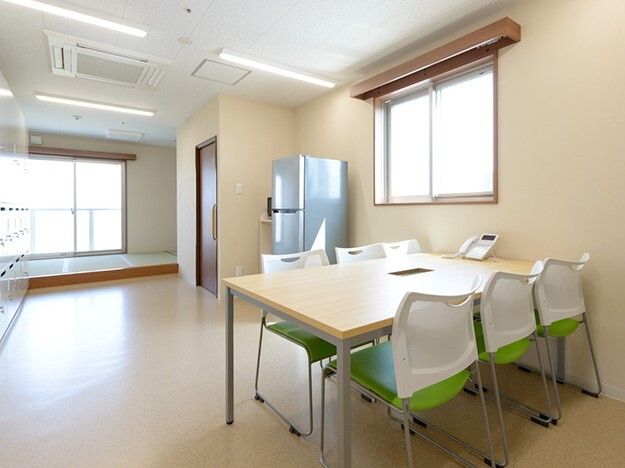 冷蔵庫や6人掛けのテーブルセットが設置された部屋には大きなロッカーも付いている。明るい雰囲気。