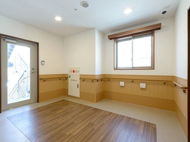 屋外階段に続くガラスのドアが付いたホールには防災設備もあり、壁には手すりが付いている。