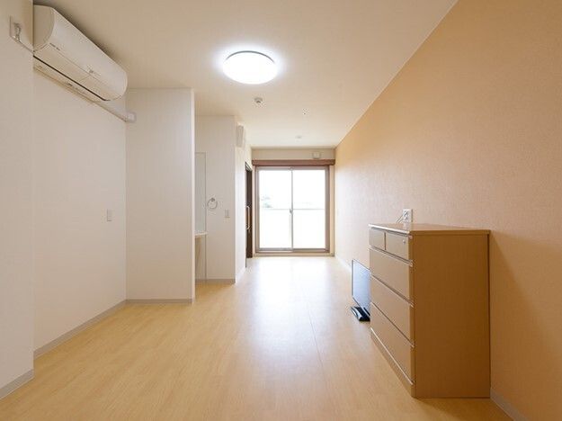 エアコンが付いたフローリングの部屋にはタンスやテレビがあり、突き当りには大きな窓が設置されている。