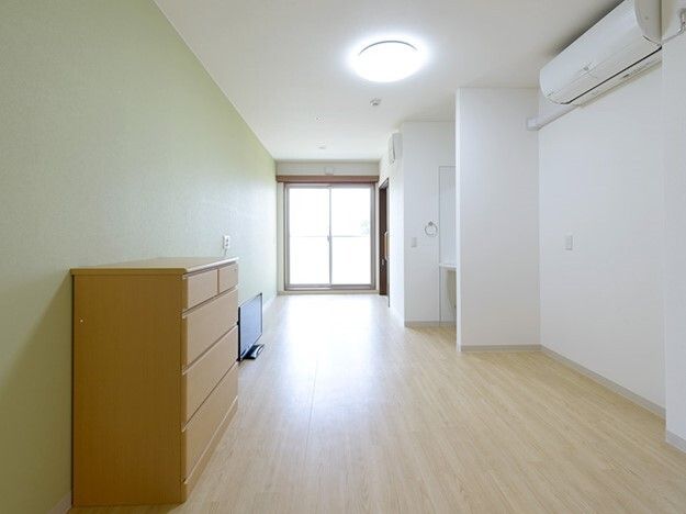 タンスやテレビが付いたフローリングの部屋にはエアコンがあり、奥には洗面所やトイレも設置されている。