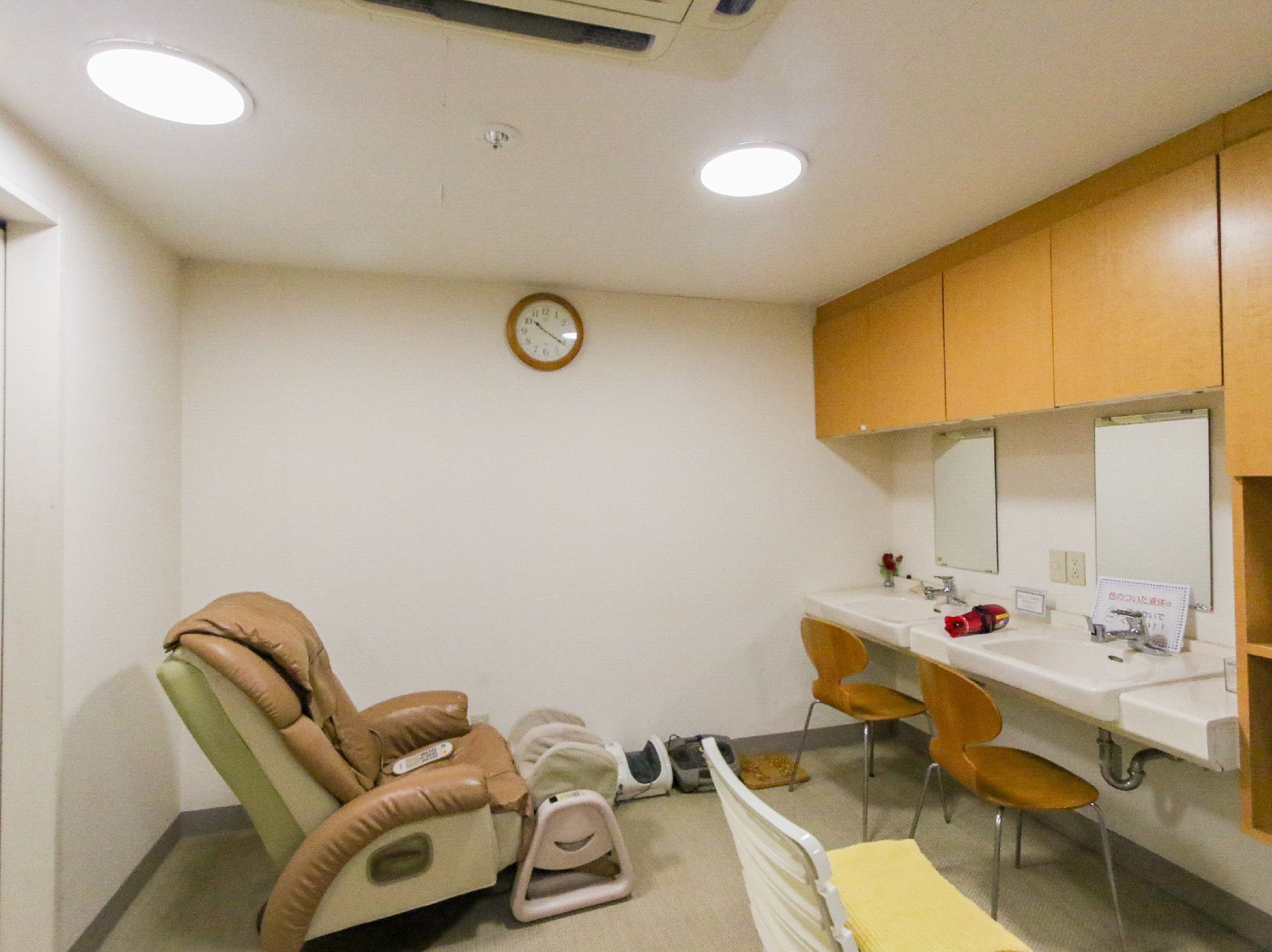 鏡が取り付けられ、洗髪用の流し台、椅子が設置されている理美容室