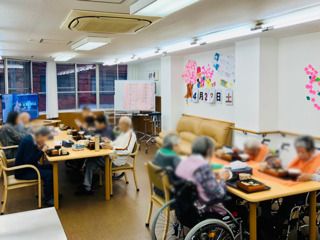 日当たりのいい場所で話している高齢女性とエプロンを付けた女性スタッフ。スタッフはカルテのようなものを見ている。