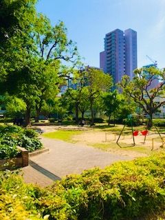遊歩道の真ん中に立ち止まり、微笑んでいる車いすの高齢女性と付き添いの若い女性スタッフ。