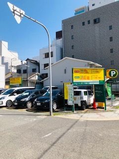黄色とグリーンの看板が建てられているコインパーキング。赤い文字で値段が書かれている。