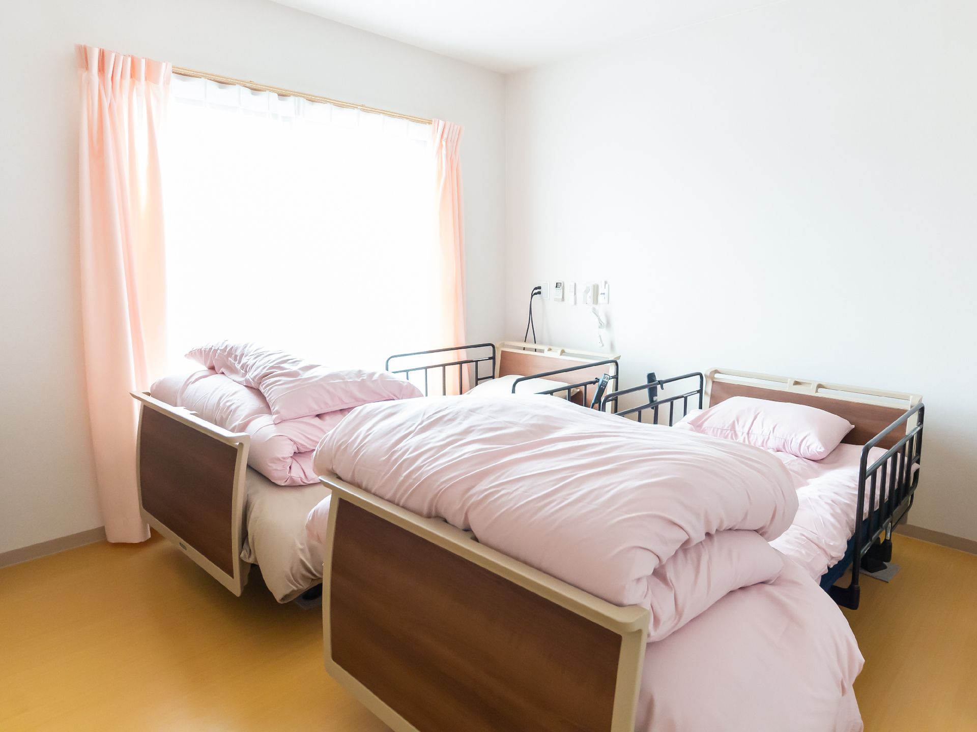 鏡を見ながら笑顔で話している高齢者とそこに寄り添介護スタッフの様子。明るい室内の写真