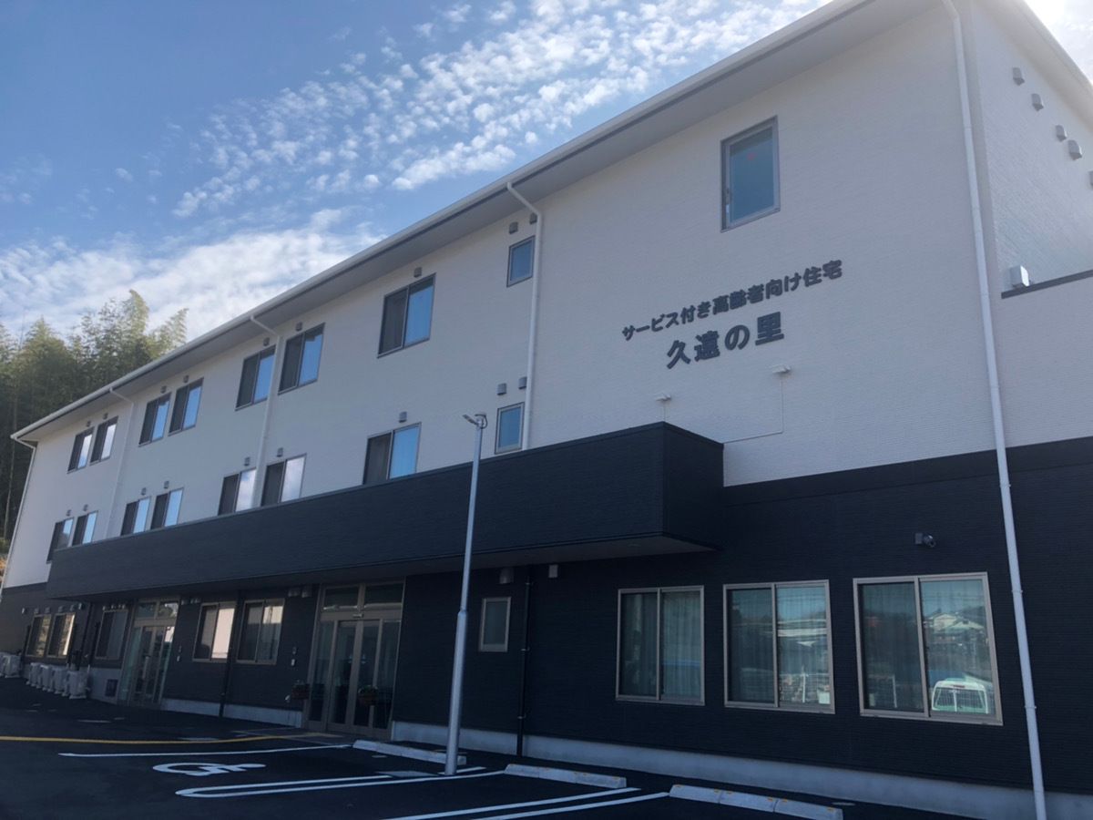 鏡を見ながら笑顔で話している高齢者とそこに寄り添介護スタッフの様子。明るい室内の写真