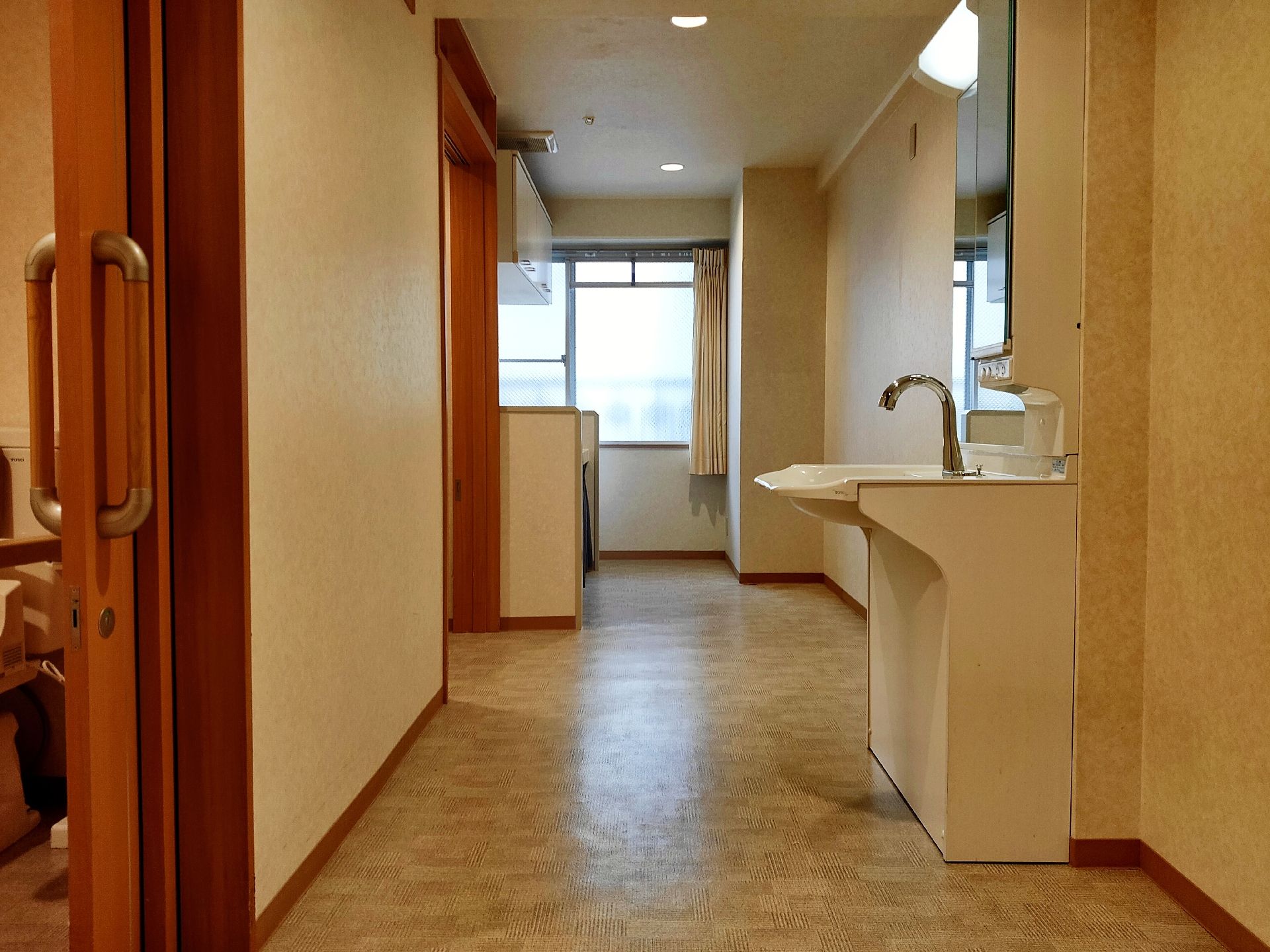 右側には鏡や照明が付いた車いす対応の洗面所が車いあり、左側にはトイレが設置されたドアが付いている。