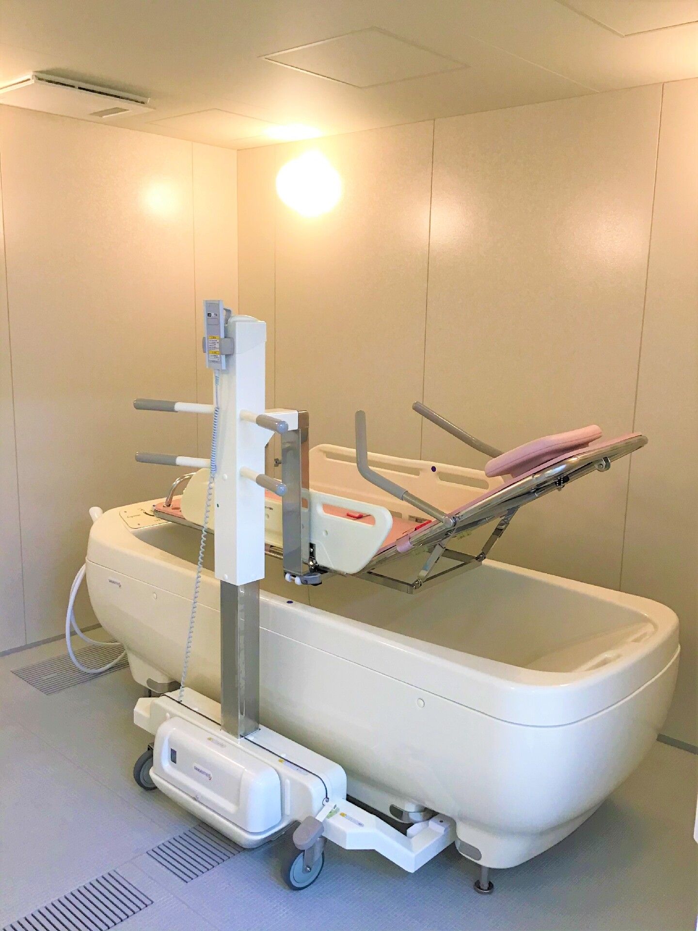 寝たままの姿勢で入浴可能な寝台浴が設置された浴室は明るい雰囲気。機械浴は白とピンク。