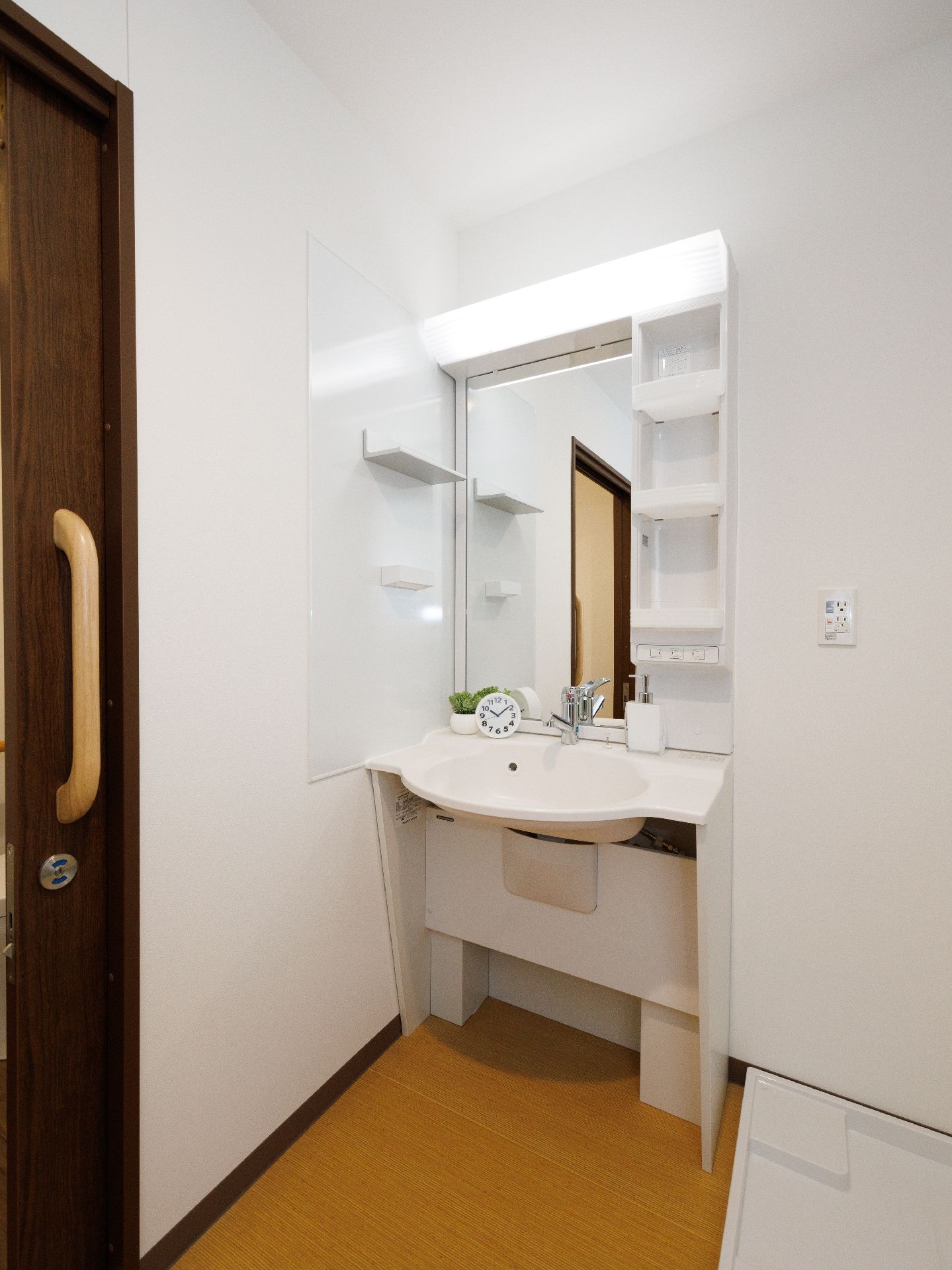 部屋の隅に置かれた鏡が付いており足元が空いている洗面台