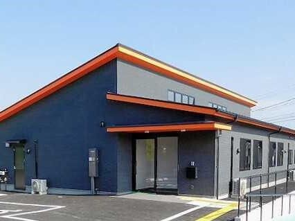 紺の外壁の平屋建ての建物が建っている敷地内には駐車スペースもあり、点字ブロックを敷かれている。