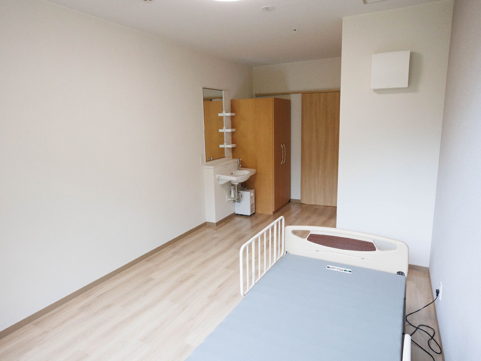 窓から日差しが差し込み、介護ベッドが置かれている居室