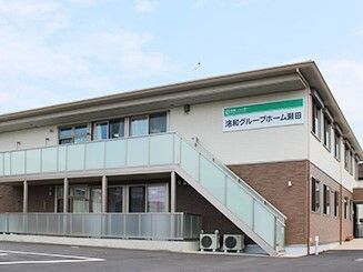 2階建ての建物は横に長く、建物の前には駐車スペースがあり、屋外階段も付いている。ホーム名が書かれた看板もある。