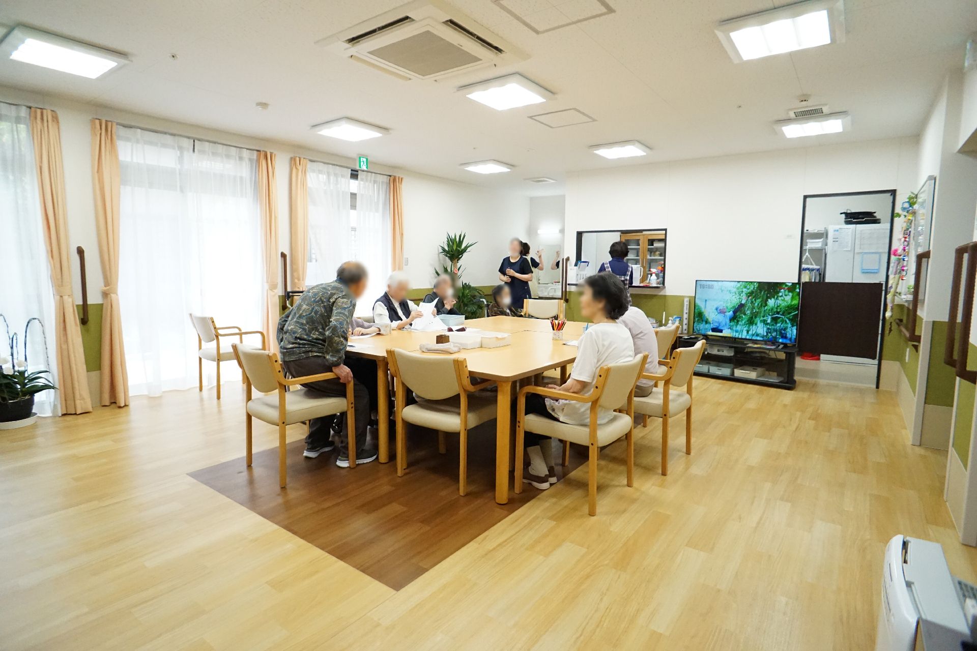 福祉車両を降りようとしている眼鏡をかけた高齢男性に手を差し出している若いスタッフ。