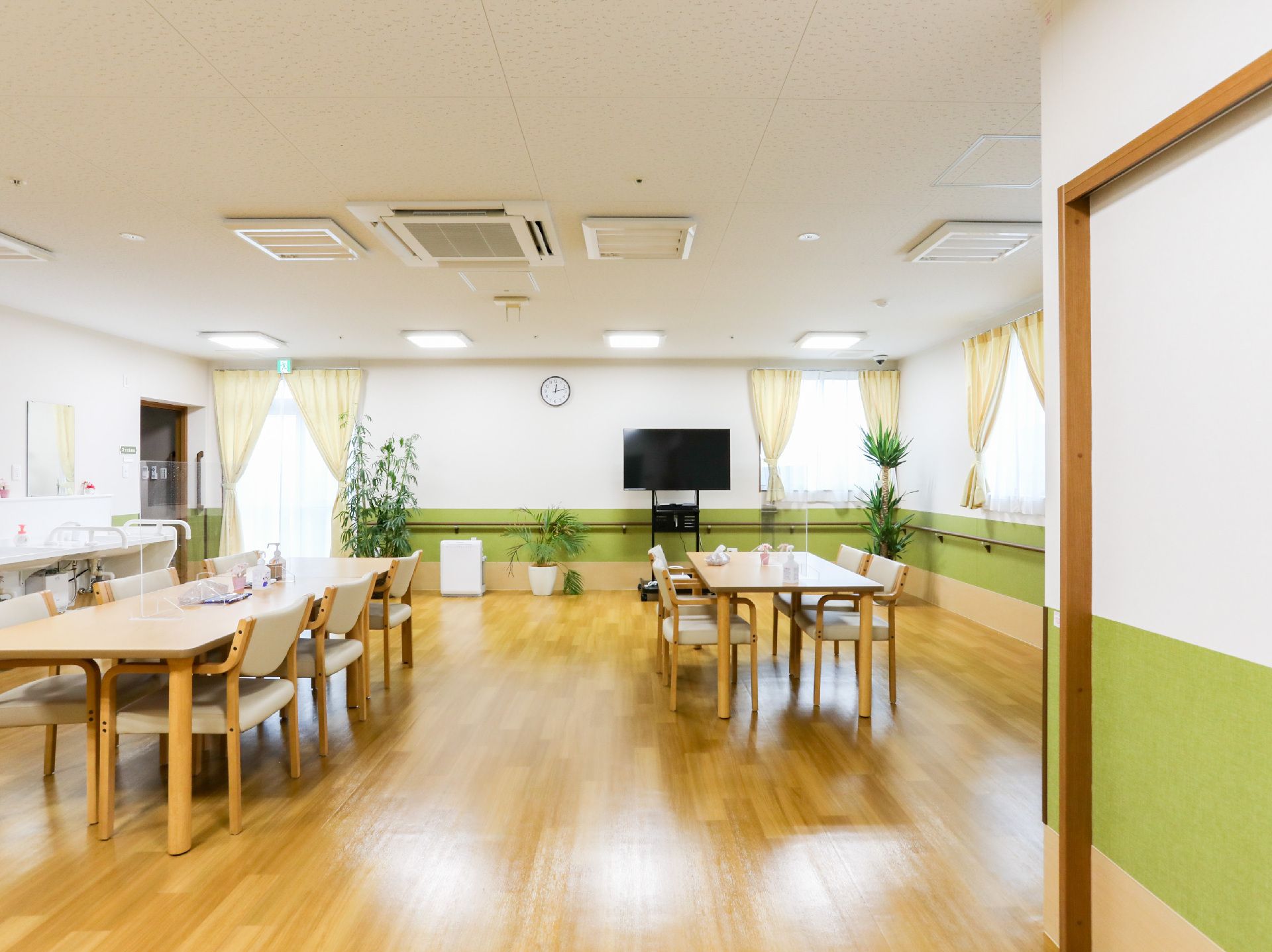 フラワーアレンジメントを楽しむ高齢男性のそばにはエプロンを付けた若い女性スタッフがいて手伝っている。