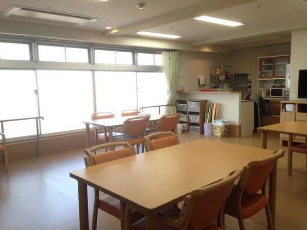 大きな窓が付いた食堂には4人掛けのダイニングテーブルセットが複数置かれ、対面式のキッチンがある。
