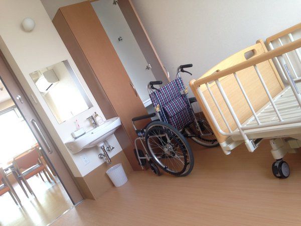 車いすが置かれた部屋にはクローゼット、車いす対応の洗面所があり、介護ベッドも置かれている。