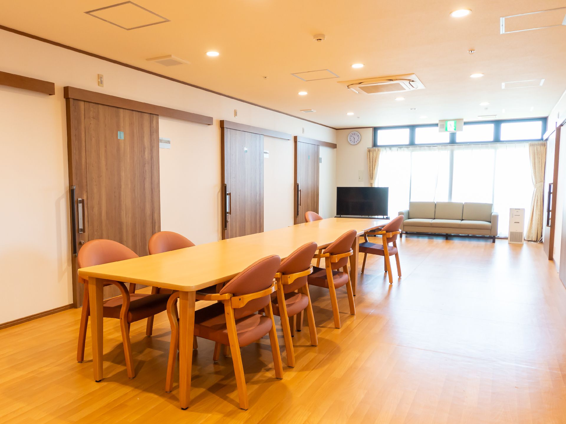 薬を飲もうとしている高齢女性のそばには水の入ったコップを持った女性スタッフがいて、微笑んでいる。