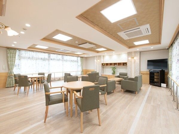 テレビがあり、木製のダイニングテーブルセットが置かれた共有スペースには大きな窓があり、カーテンも付いている。