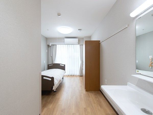 フローリングの部屋には寝具付きのベッドが置かれ、車いす対応の洗面所やエアコンも付いている。