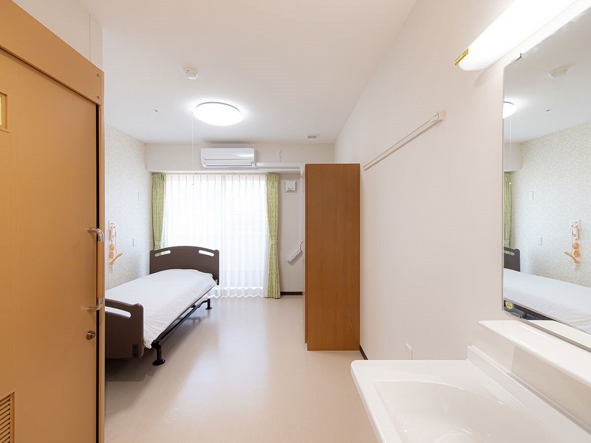 クローゼットや寝具付きのベッドが置かれ、車いす対応の洗面所やトイレが付いた部屋。