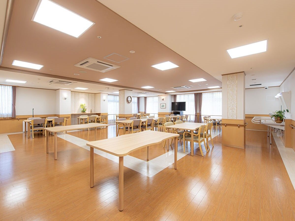 木製のダイニングテーブルセットが複数置かれ、明るい雰囲気。テーブルの一部には椅子がセットされている。