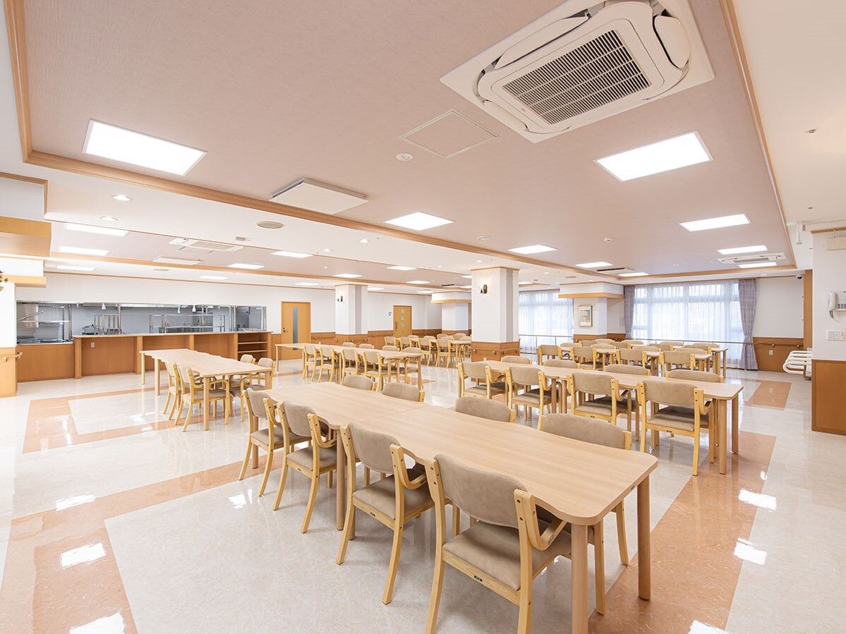 木製のダイニングテーブルセットが複数置かれ、奥には厨房があり、中を見ることができる。