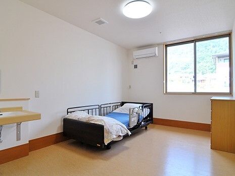エアコンが付いた広い部屋には寝具がセットされたベッドが置かれ、大きな窓が付いている。