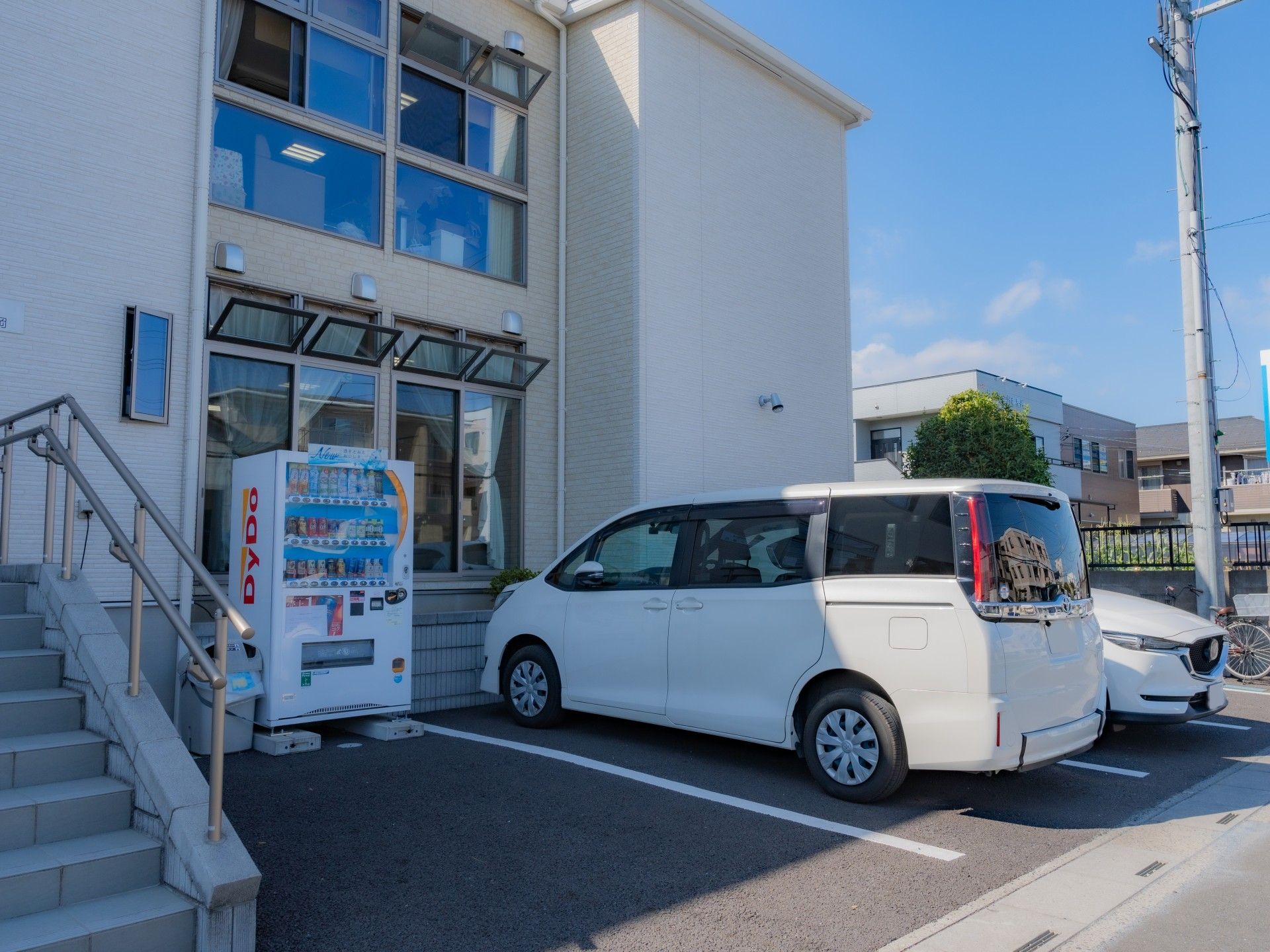 2台の車が駐車しており、横には自動販売機が設置されている