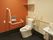 呼び出しボタンや手すりが付いた広いトイレにはふたのない便座が設置されている。
