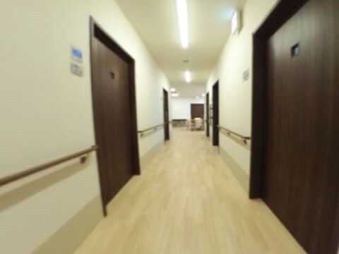 まっすぐな廊下の両サイドに手すりと居室のドアがあり、歩行の邪魔となるものはない。