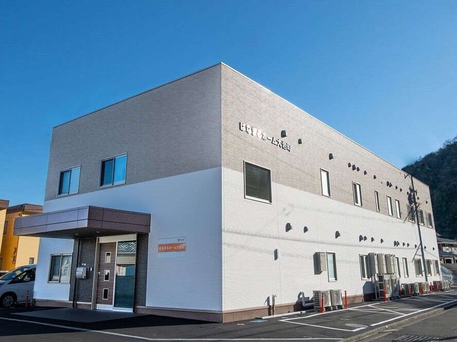 駐車場もある２階建ての建物は日当たりのいい場所に建っている。玄関先には屋根がある。