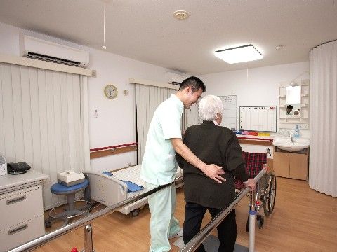 スタッフに支えられながら、機器を利用して歩行訓練をする入居者