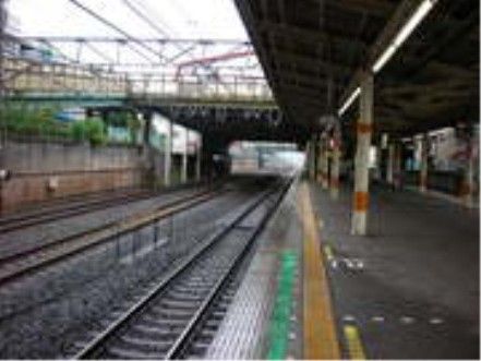 総武本線の新検見川駅のホームである。前面には複線の線路があり、ホームの屋根の上には陸橋が架かっている。