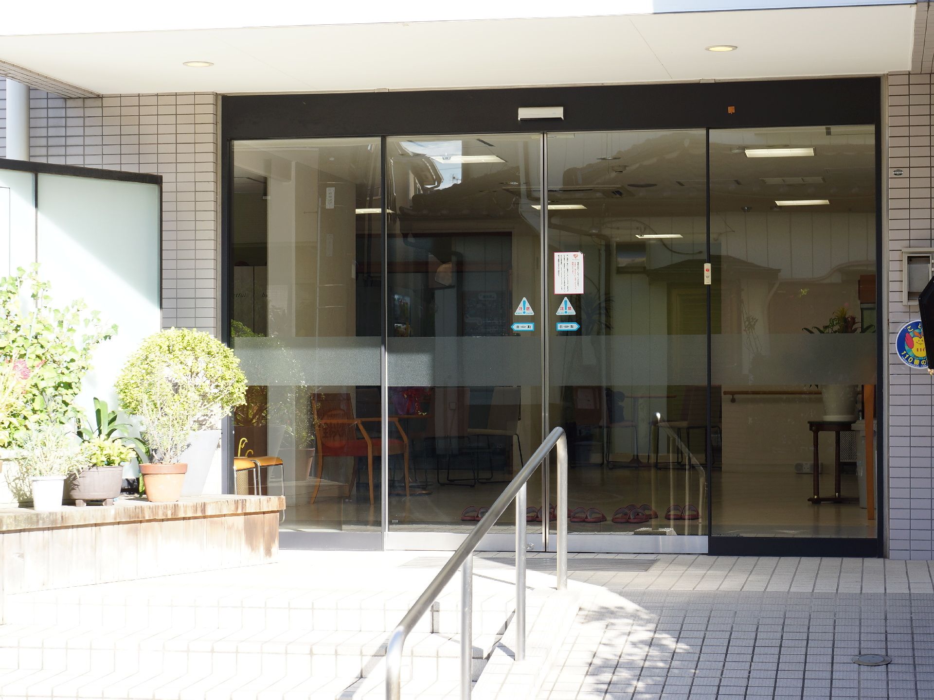施設の入口は自動ドア方式になっており、その向こう側のエントランス部分にはスリッパが置かれているのが見える。