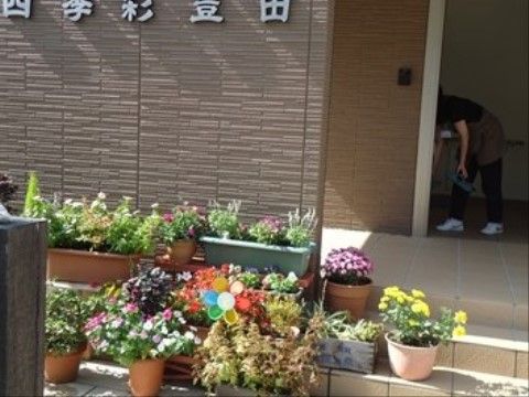 「四季彩 豊田」の外観2。季節の花が並んでいる。