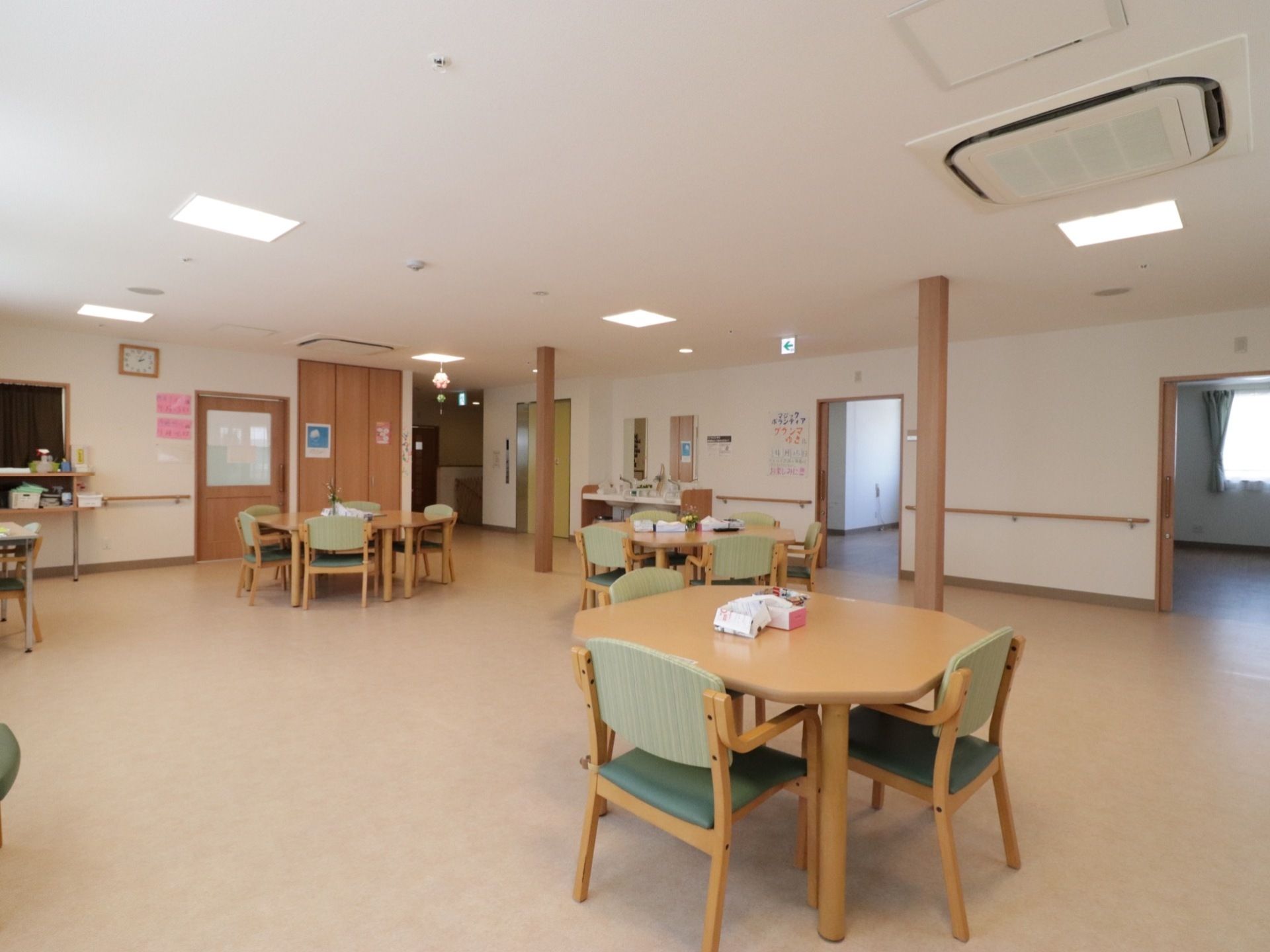 肘掛け椅子がセットされた4人掛けテーブルが、間隔を開けて置かれている。エアコンは天井に埋め込まれている。