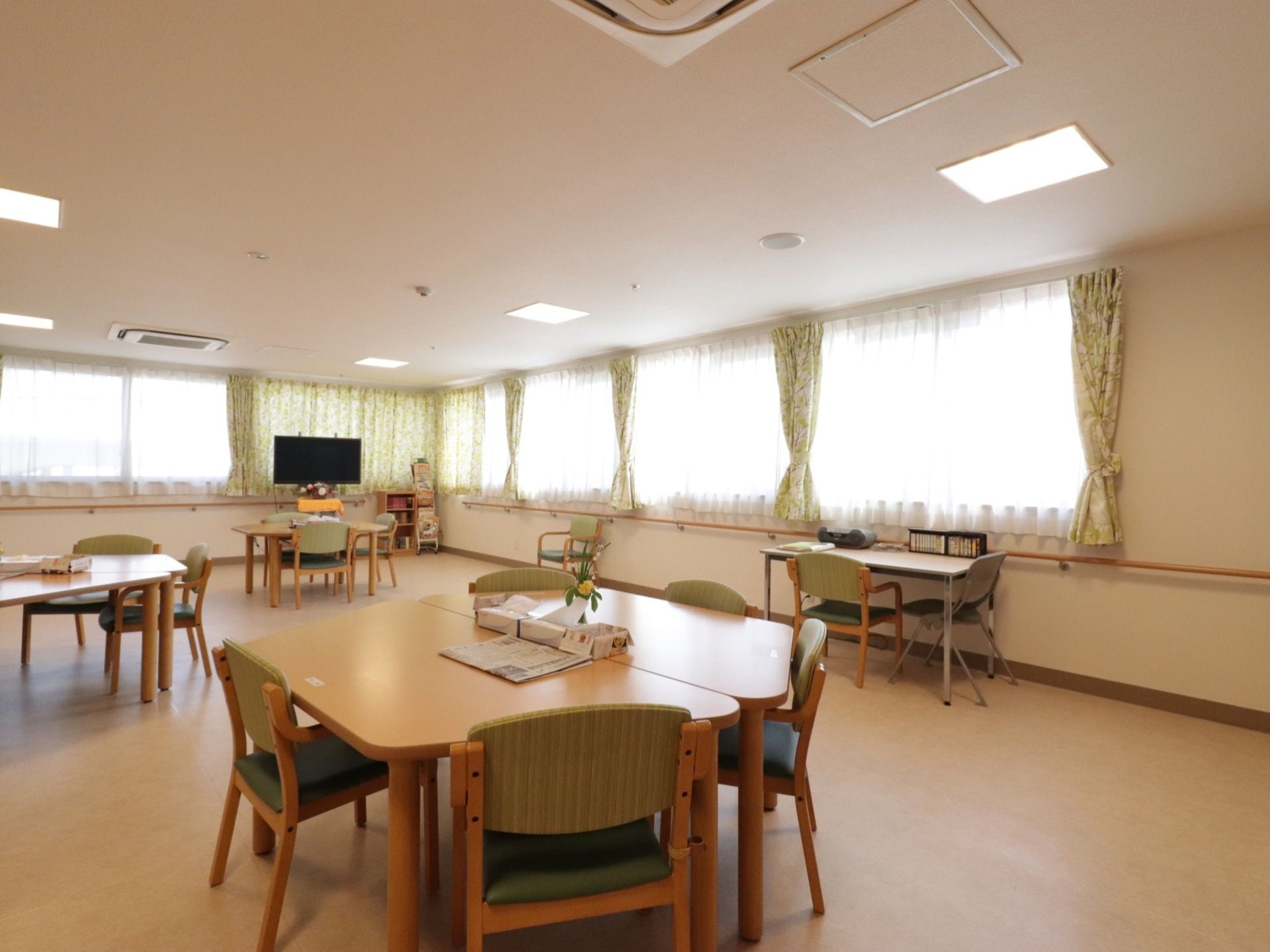 建物の角にあり、突き合わせの壁一面に腰高窓がはめられている。天井に埋め込み式のエアコンがある。椅子とテーブルのセットがいくつかある。