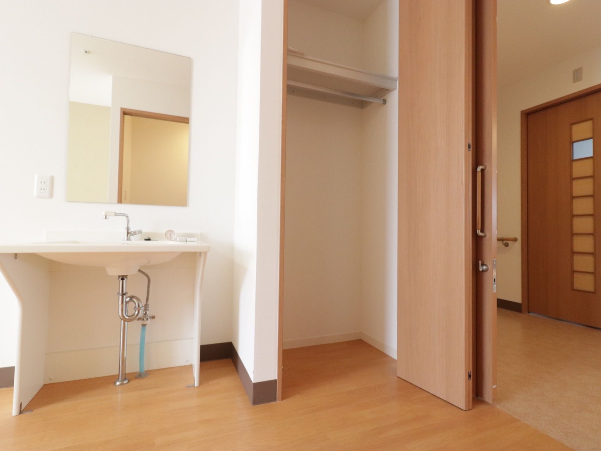 居室に入って右には、クローゼットがあり、続いて洗面台が設置してある。フローリングの床と入口のドアには、木目が見える材料を用いている。