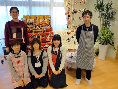季節のイベントにちなんだ飾りつけの前で並んで微笑んでいる５名のスタッフ