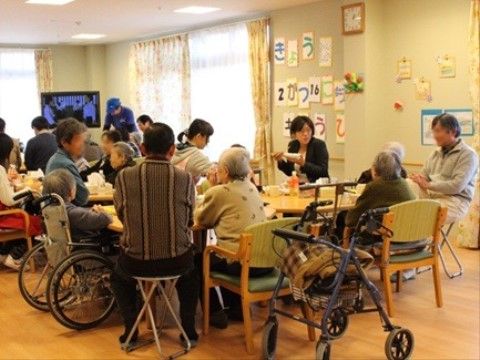 ダイニングルームで入居者と訪問者の方々が集まって食事を楽しむ光景
